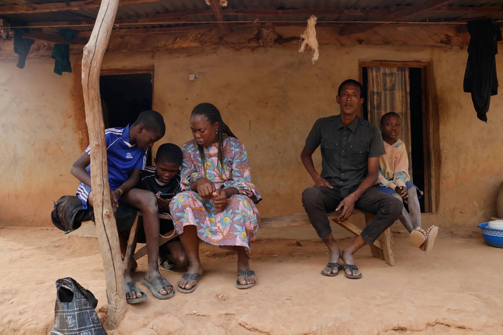 Precious Njikonye, center, the mother of a student at St. Mary's Catholic School, who was abducted by gunmen and later released, sits outside her house in Papiri, Nigeria, Wednesday, Dec. 10, 2025. (Credit: Afolabi Sotunde/AP.)
