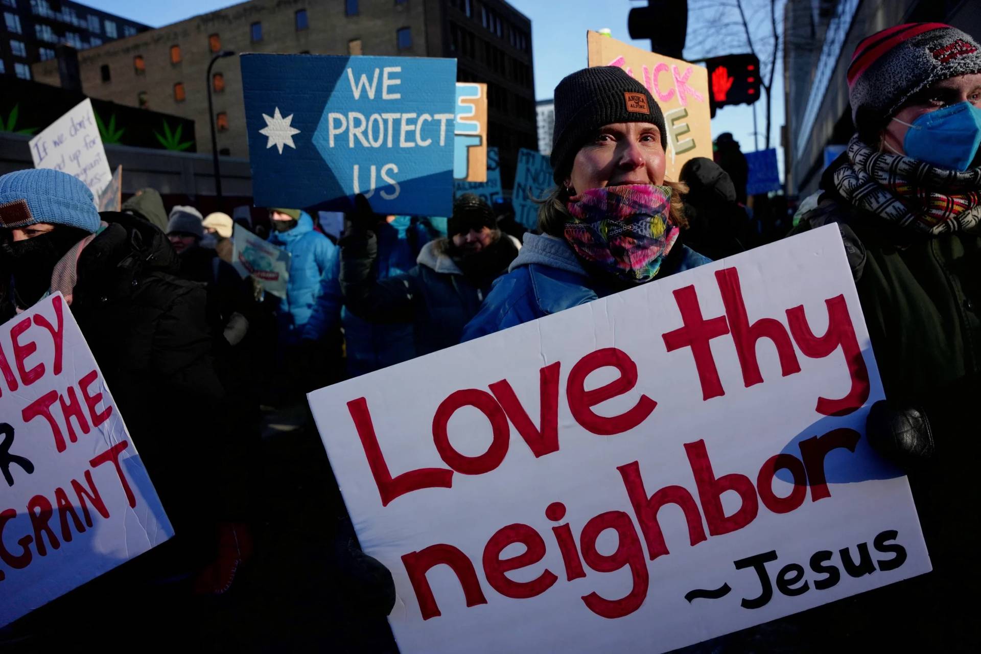 A protester holds a sign reading "Love thy neighbor - Jesus" during a rally against federal immigration enforcement on Friday, Jan. 23, 2026, in Minneapolis. (Credit: Angelina Katsanis/AP.)